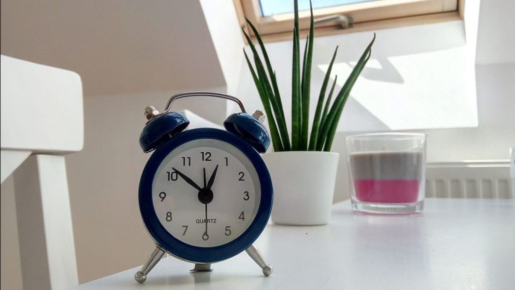 A desk with a clock and a plant on it.